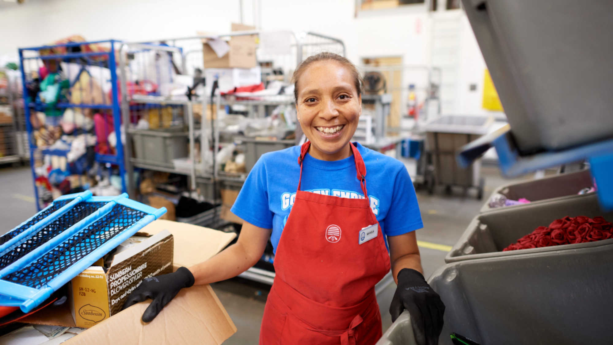 A Deseret Industries employee smiles as she sorts donations into bins for pricing in the back room